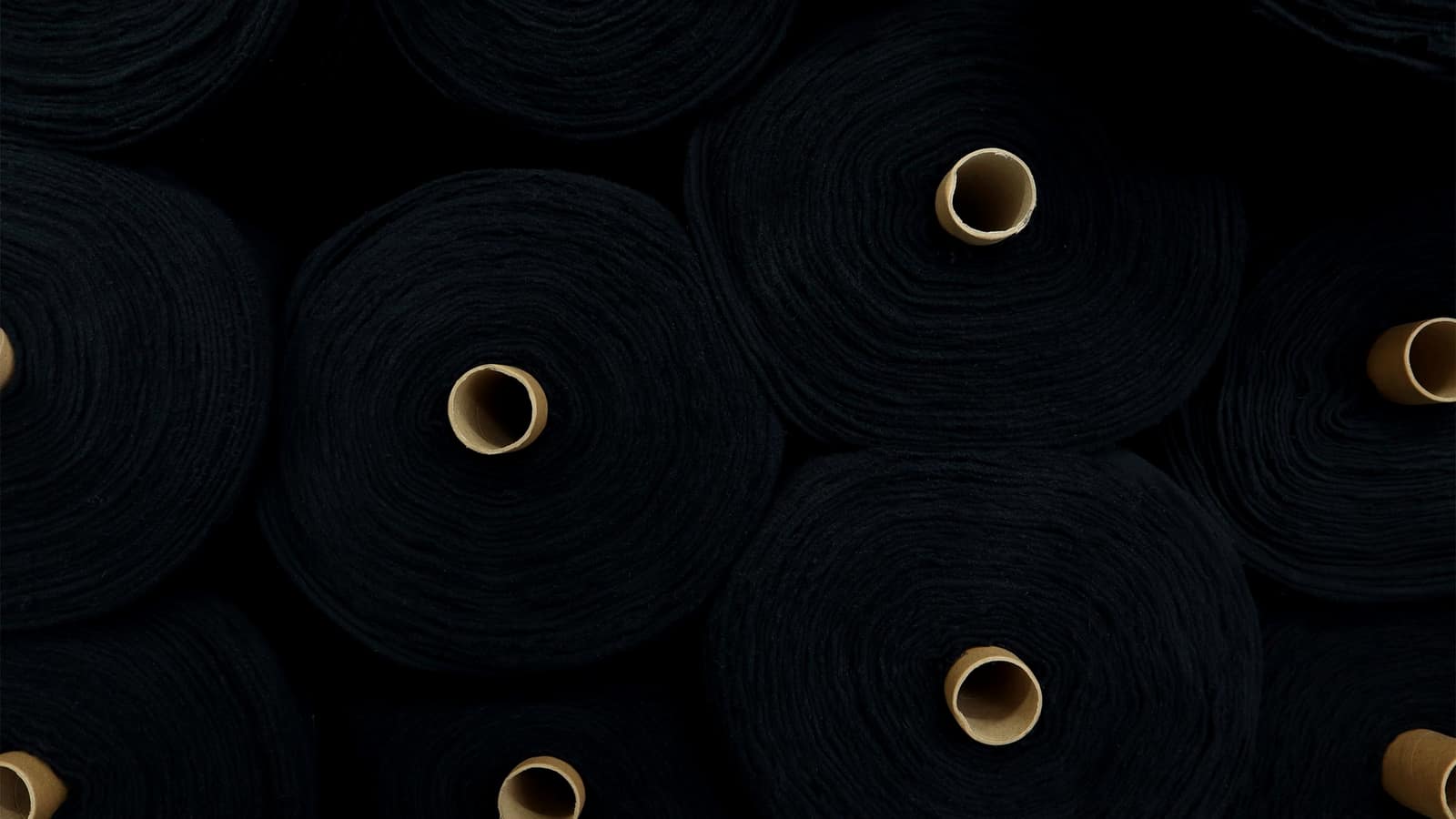 Rolls of black fabric stacked end-on in a factory store