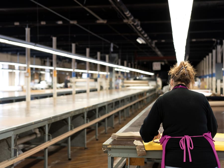 A pattern hand working at the end of a long row of cutting tables