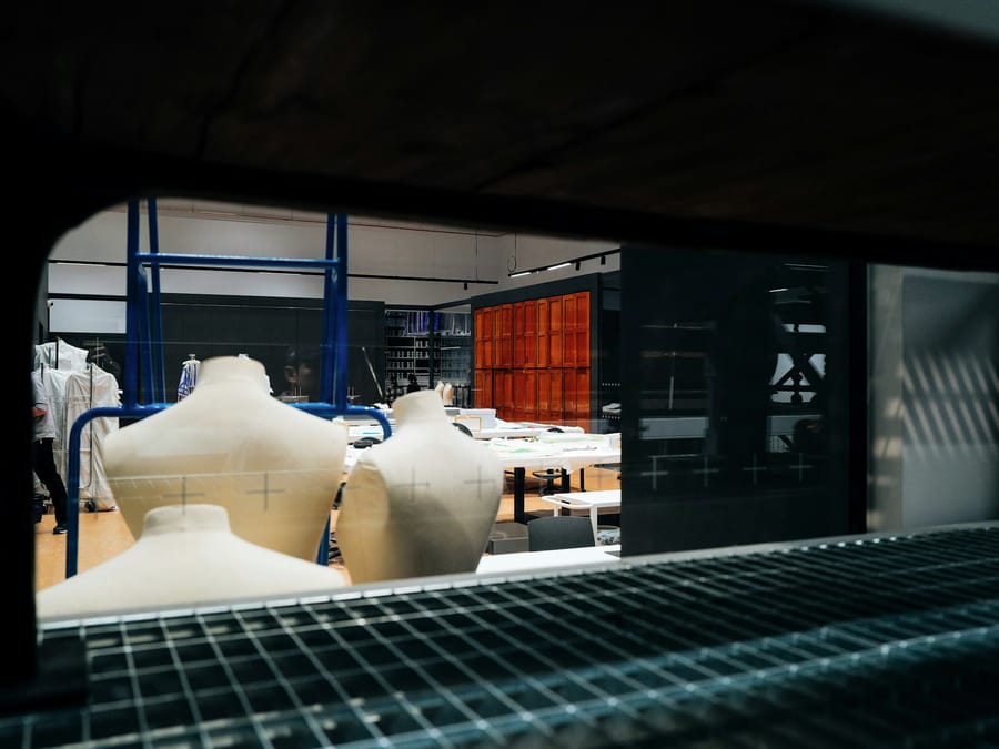 A row of dress forms in front of pattern tables in a sample room