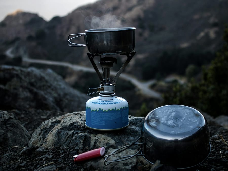 A canister stove and pan on a rock above a coast road