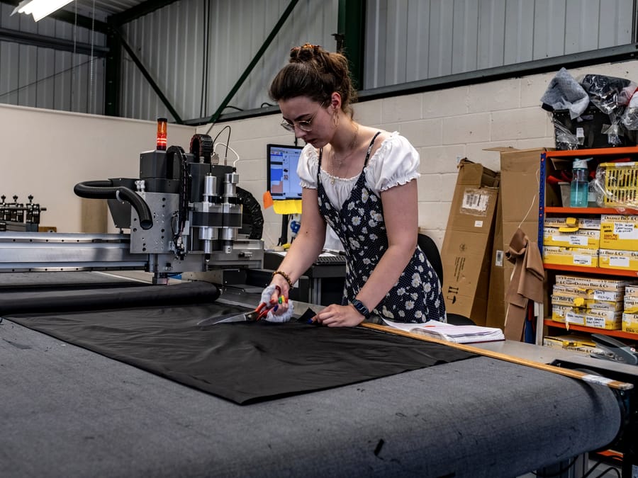 A cutter working at an automated cutting table in a small garment factory