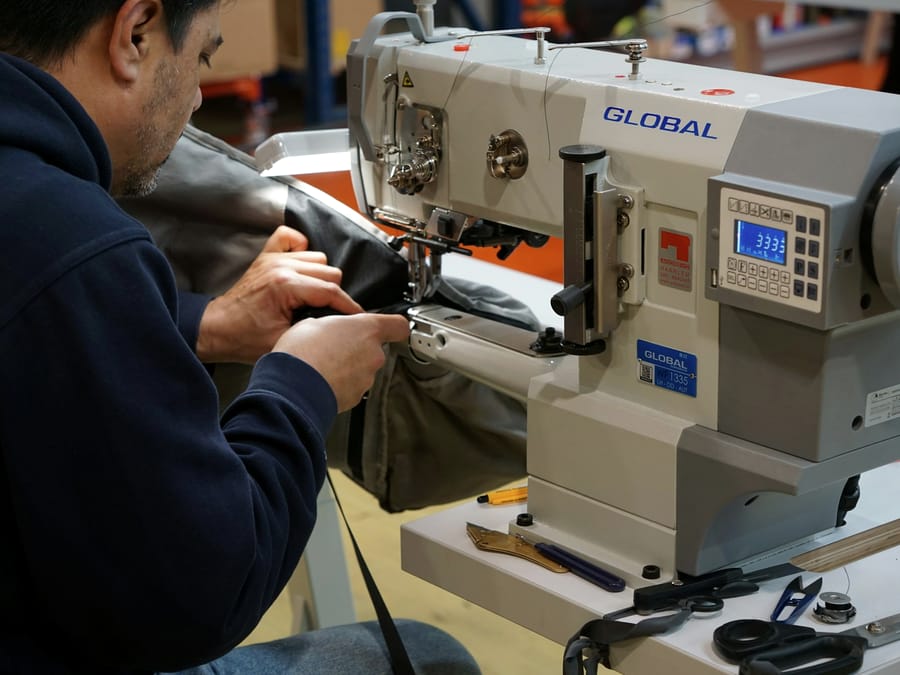 Hands feeding fabric through an industrial sewing machine